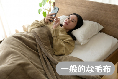 一般的な毛布を被ってスマホを使う女性
