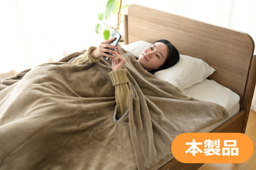 本製品により、首元や肩まで毛布を被ってスマホを使う女性