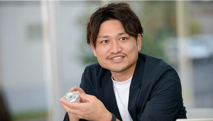 アルミパーツを片手に、山善とHILLTOPの出会いについて話す吉田様